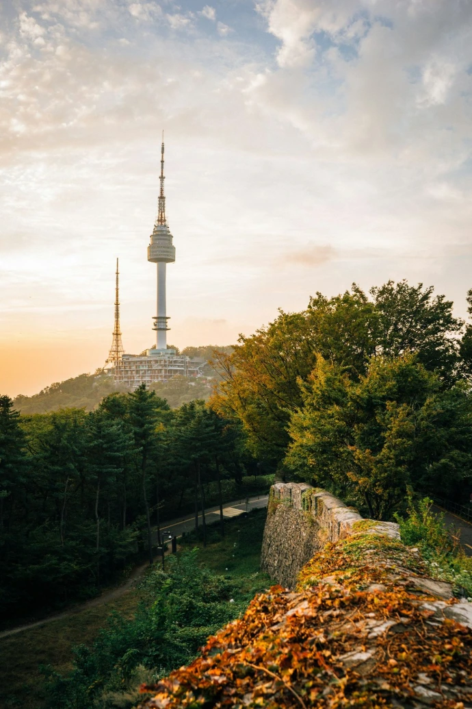Namsan Tower rising above a forested hill and stone wall in Seoul, South Korea